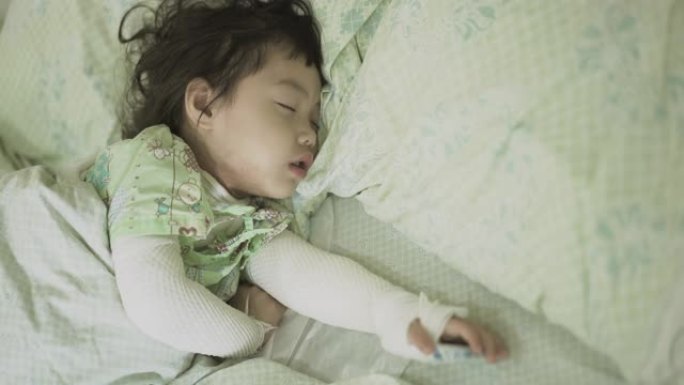 亚洲小女孩躺在医院的床上，女婴因皮肤过敏而生病，她被绷带包裹在脖子和双臂上，特应性皮炎 (AD)。手