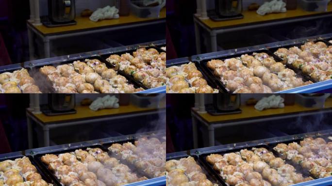 厨师手在章鱼锅烹饪日本小吃章鱼烧的4k特写镜头，在日本东京街头食品市场出售。男子手工准备日本传统美食