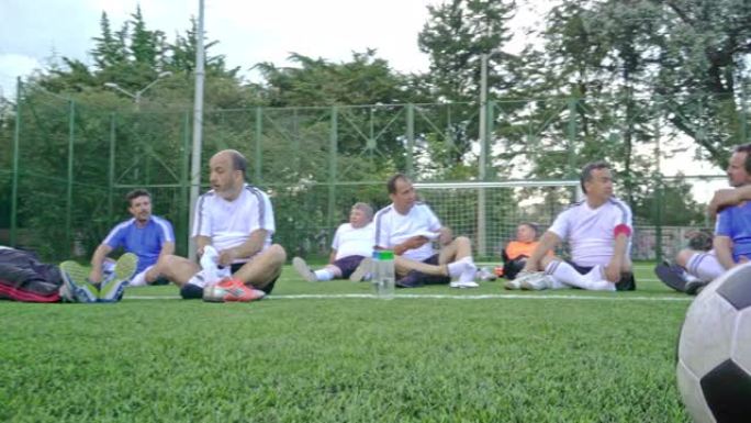 赛后球员和其他球员一起坐在球场上放松