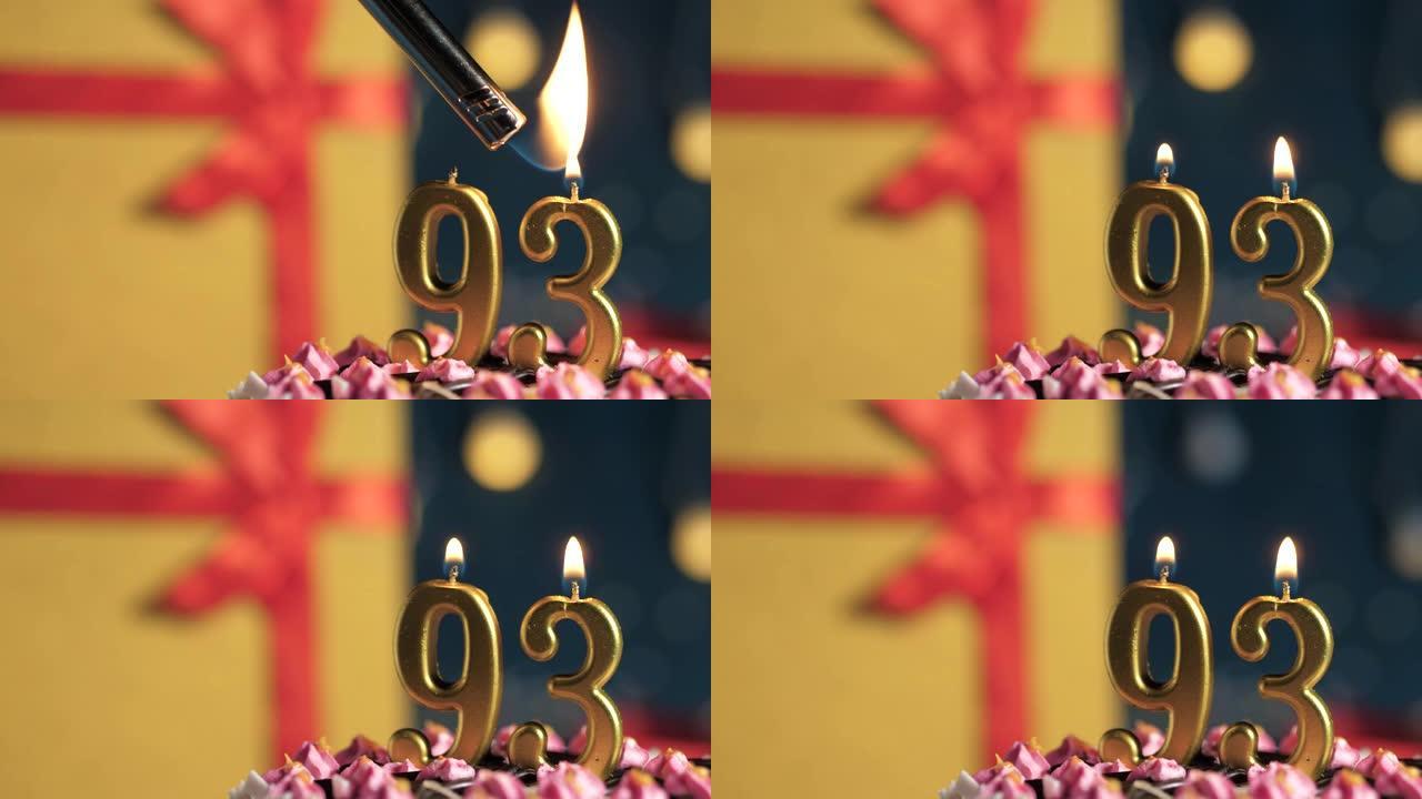生日蛋糕93号点火器燃烧的金色蜡烛，蓝色背景礼物黄色盒子用红丝带绑起来。特写和慢动作