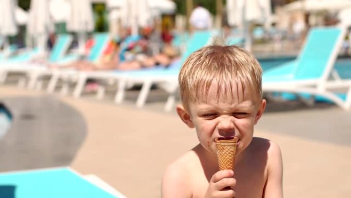 暑假，一个小孩在游泳池附近吃巧克力冰淇淋。