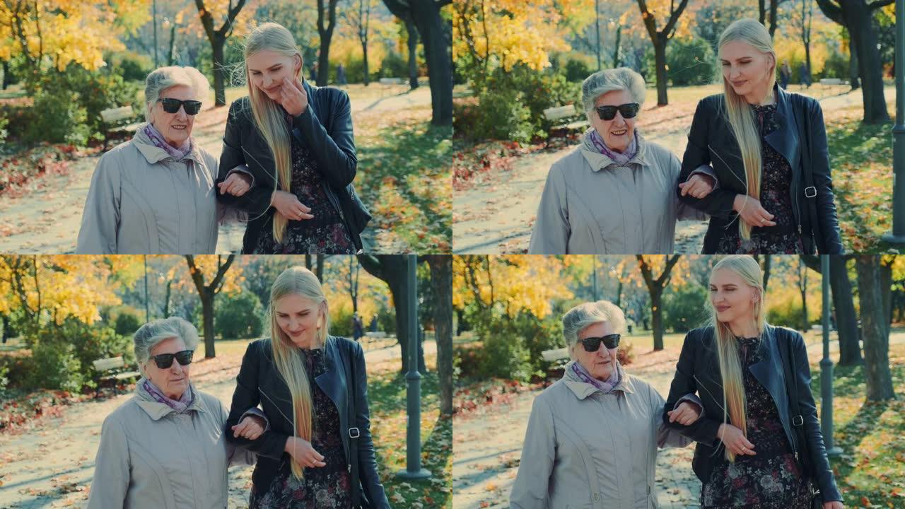老妇人和快乐的金发女孩一起在秋公园散步
