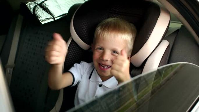 一个开朗的小男孩坐在棕色的儿童汽车安全座椅上，竖起大拇指。