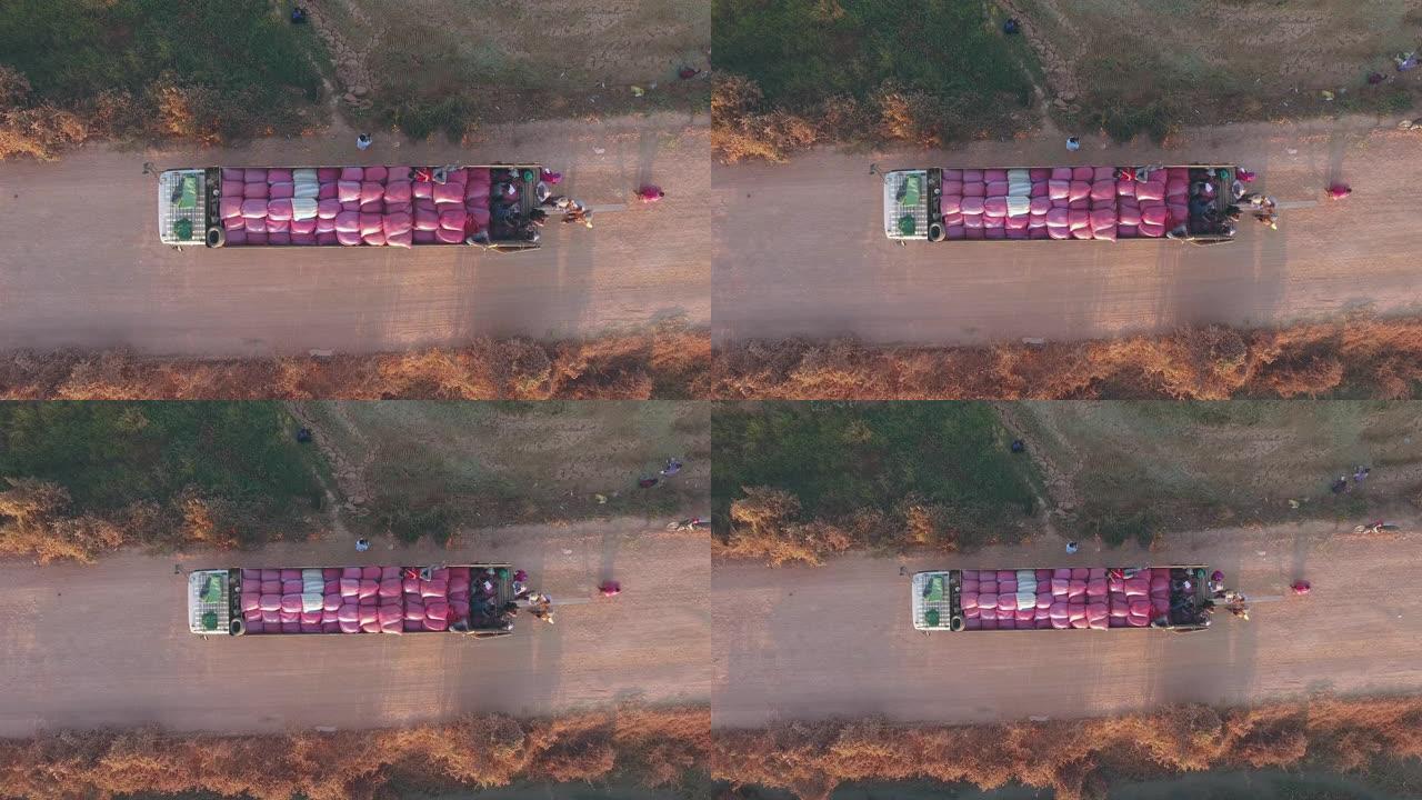 无人机拍摄的人们聚集在卡车内数数大米袋并与农民谈判价格