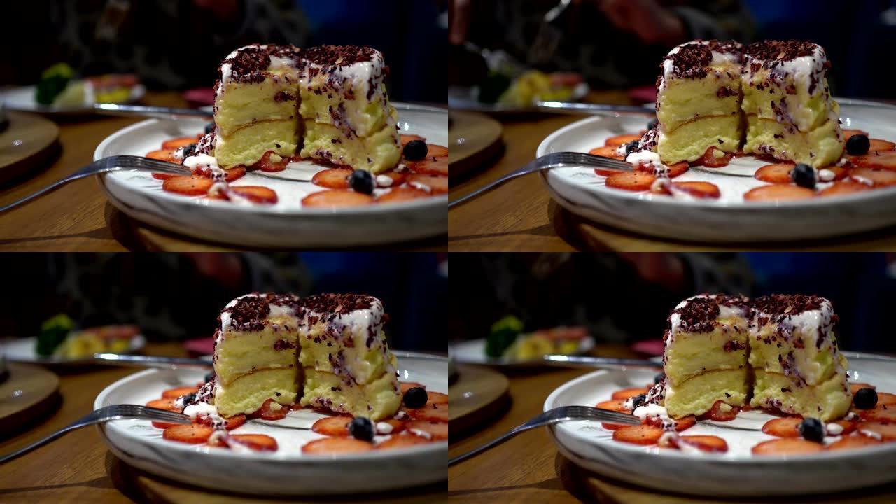 关闭切片草莓蛋糕。新鲜草莓切片，蓝莓放在盘子里。