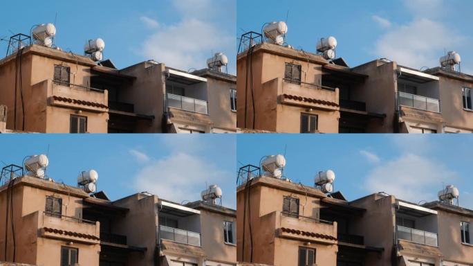 混凝土房屋的侧视图，带有露台和窗户，建筑物屋顶上有水箱。屋顶上的太阳能热水器锅炉