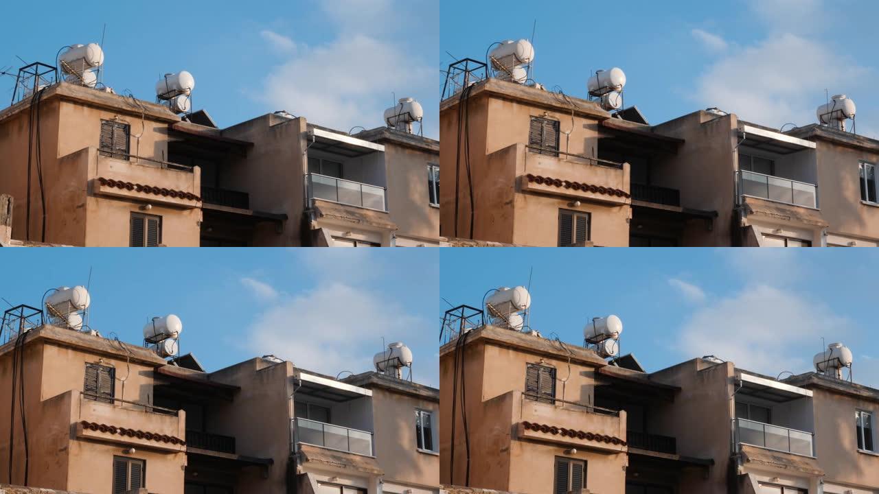 混凝土房屋的侧视图，带有露台和窗户，建筑物屋顶上有水箱。屋顶上的太阳能热水器锅炉