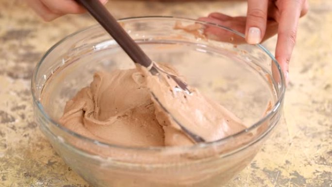 用硅胶铲搅拌巧克力奶油。特写。