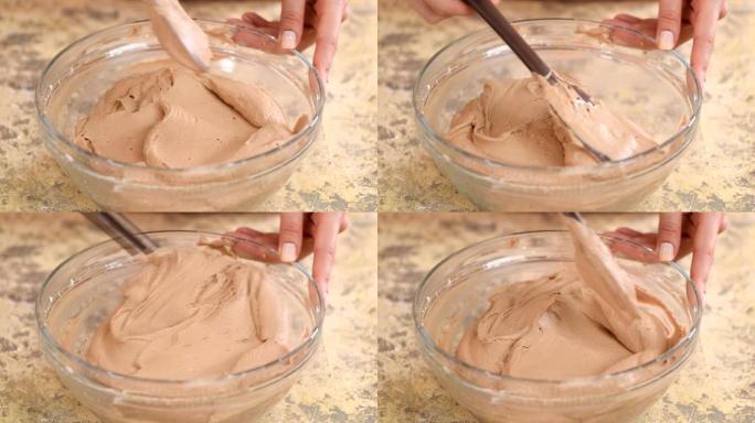 用硅胶铲搅拌巧克力奶油。特写。