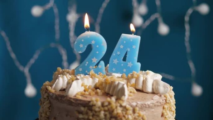 蓝色背景上有24号蜡烛的生日蛋糕。蜡烛吹灭了。慢动作和特写视图