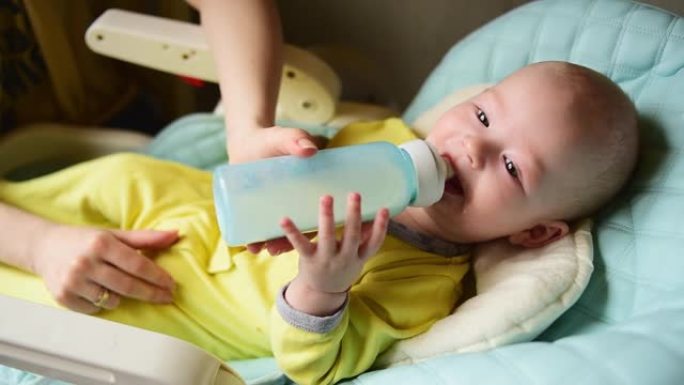 母亲用奶瓶中的婴儿配方奶粉喂养婴儿