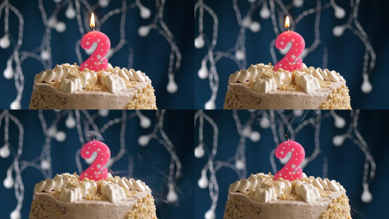 蓝色背景上有2个数字粉色蜡烛的生日蛋糕。蜡烛吹灭了。慢动作和特写视图