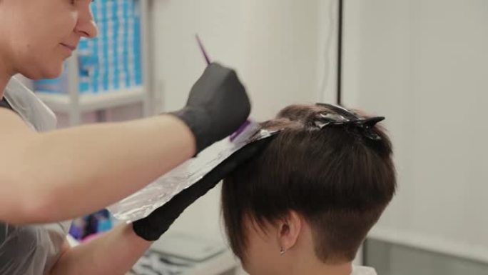 专业美发师女人用铝箔染发剂染发女孩的头发