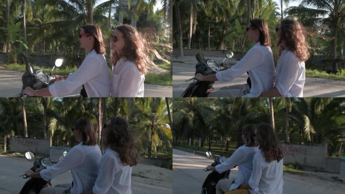 年轻漂亮的女孩在热带的路上骑自行车。自由快乐的女孩在微笑。戴眼镜的女孩在微笑。两个去椰子种植园。