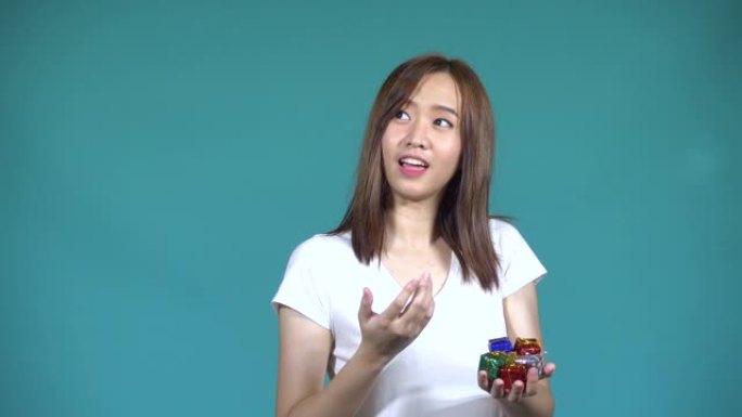 亚洲快乐美丽可爱的年轻女子青少年她手边扔小礼品盒，看着工作室里的相机，孤立在蓝色背景上，4k视频解决