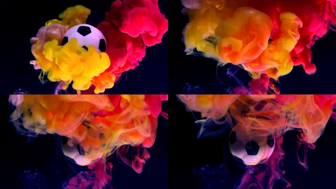 火热背景下的足球。黑色背景上的黄色，红色和橙色墨水在水中。