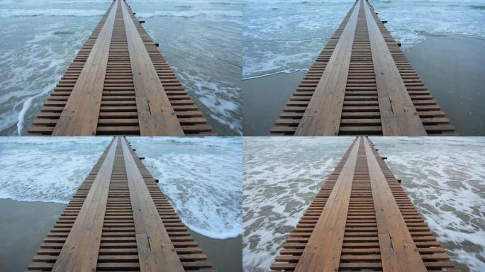 加速视频拍摄海浪在沙滩上滚动，一个码头进入大海