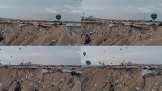 卡帕多西亚日出时，五颜六色的热气球在白雪皑皑的童话烟囱上