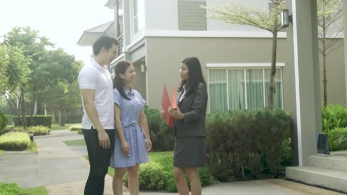 幸福的亚洲夫妇寻找他们的新房子，并在交易后与房地产经纪人握手。年轻夫妇签署购房合同后握手房地产经纪人