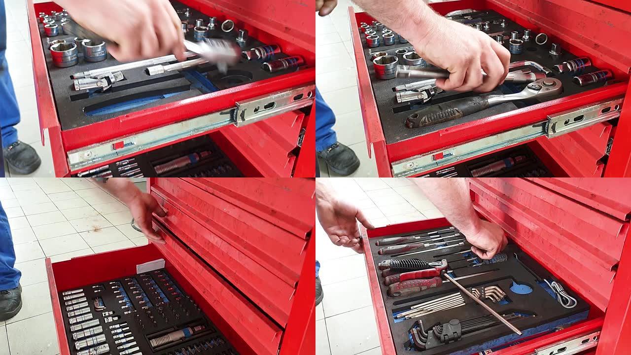 该男子将工具放入工具箱的孔中，汽车车间的红色铁箱