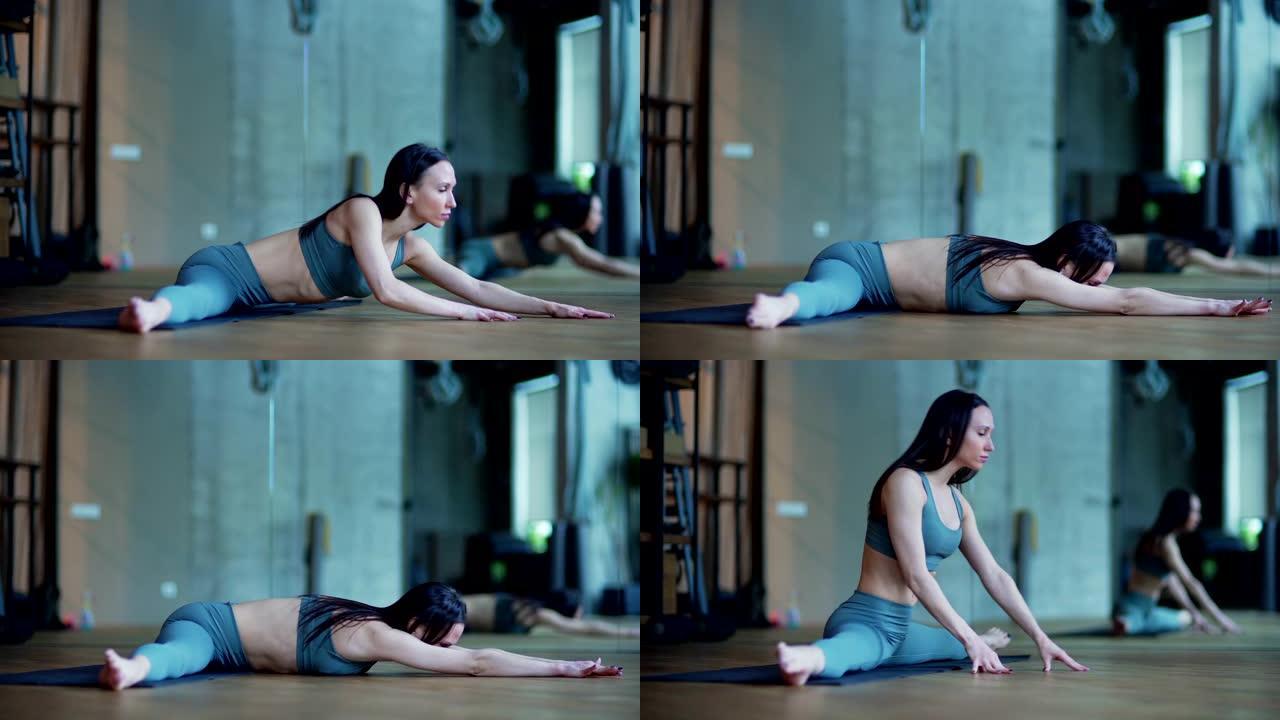 灵活的女瑜伽教练在瑜伽馆练习时在垫子上进行大范围的锻炼的侧视图