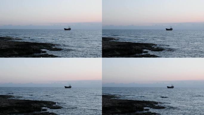 老生锈的船搁浅在岩石海岸。美丽的海景，背景是大货船。货船搁浅在海上。从岩石海岸可以看到海景。