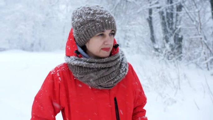 穿着红色夹克的女人在镜头前走在白雪覆盖的道路上。