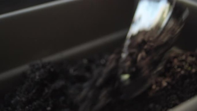 花园抹子的特写镜头在一个长的播种机箱中混合新鲜的土壤