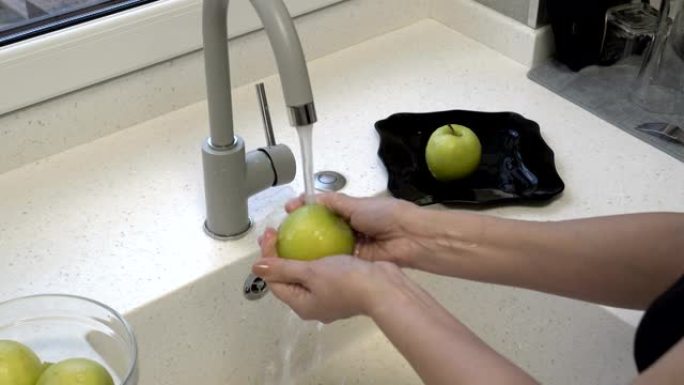 一个女人在厨房的水槽里洗青苹果。作业。健康饮食。特写。4k