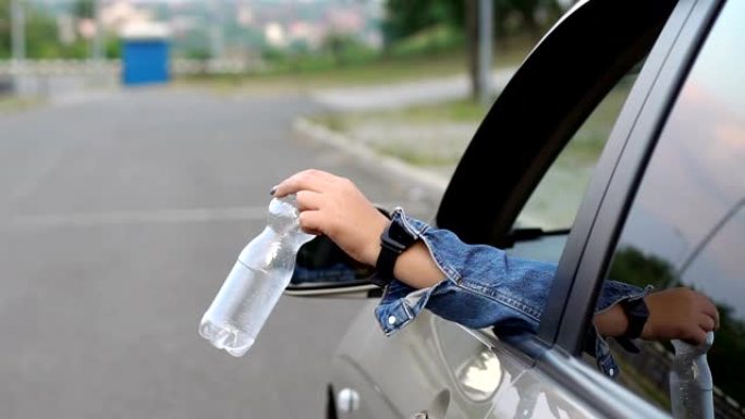 女司机在路上从车窗上扔掉塑料瓶。