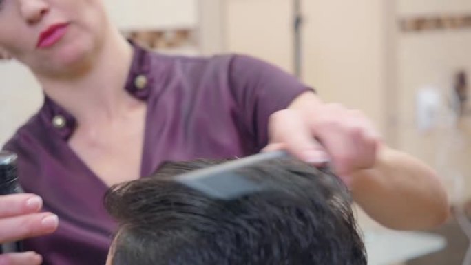 理发店的造型师，近距离拍摄。大师用发胶和梳子制作现代发型。记录在美发沙龙。