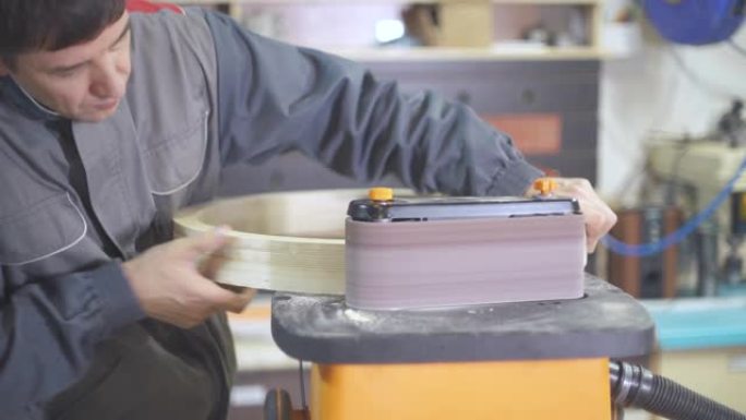 工匠在工业家具工厂车间使用研磨机。木匠工程仪器。人类在植物里工作。生产车间的设备。工艺木制品。木材加
