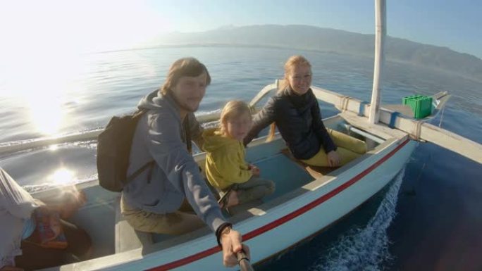 日出时，家人乘坐亚洲传统船。他们将在北巴厘岛地区的Lovina湾看到海豚。巴厘岛旅游概念