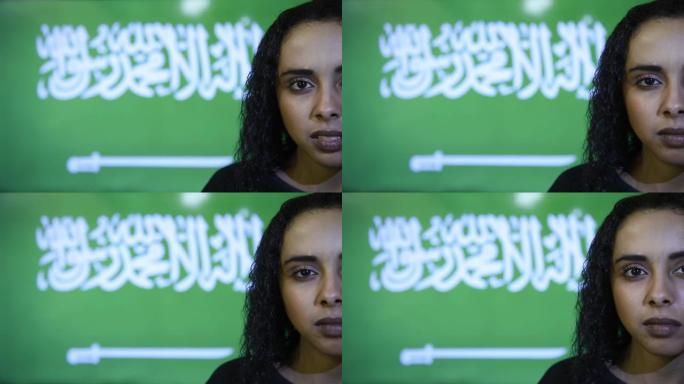 特写年轻美丽的黑发女孩，站在沙特阿拉伯国旗上