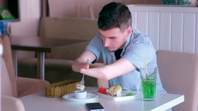 一个截了两只残手的残疾人在咖啡馆用叉子吃寿司卷。