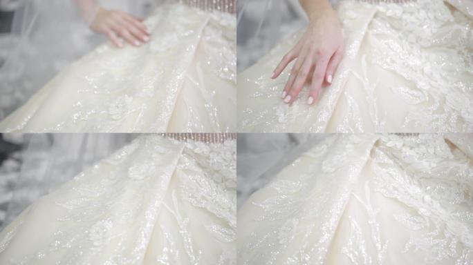 白色婚纱和面纱，新娘在上面抚摸着她的手