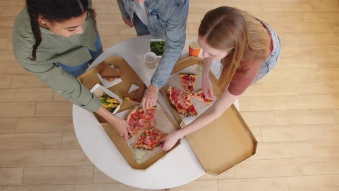 快乐的年轻多民族朋友站在家里的餐桌旁拿一块披萨