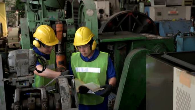 两名男性亚洲检查员，工程师在工厂的生产线过程中工作