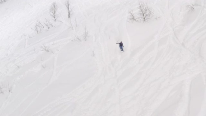 滑雪者在冬季度假胜地从白雪皑皑的坡道上骑自由车。鸟瞰滑雪者在冬季度假胜地的山坡上驾驶。从冬季运动和人