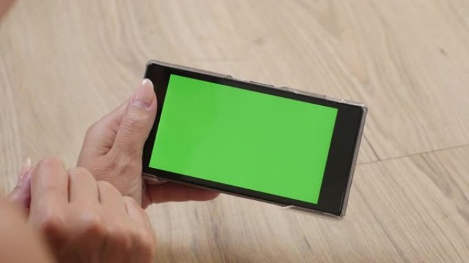 女人在家拿着绿色屏幕智能手机4K