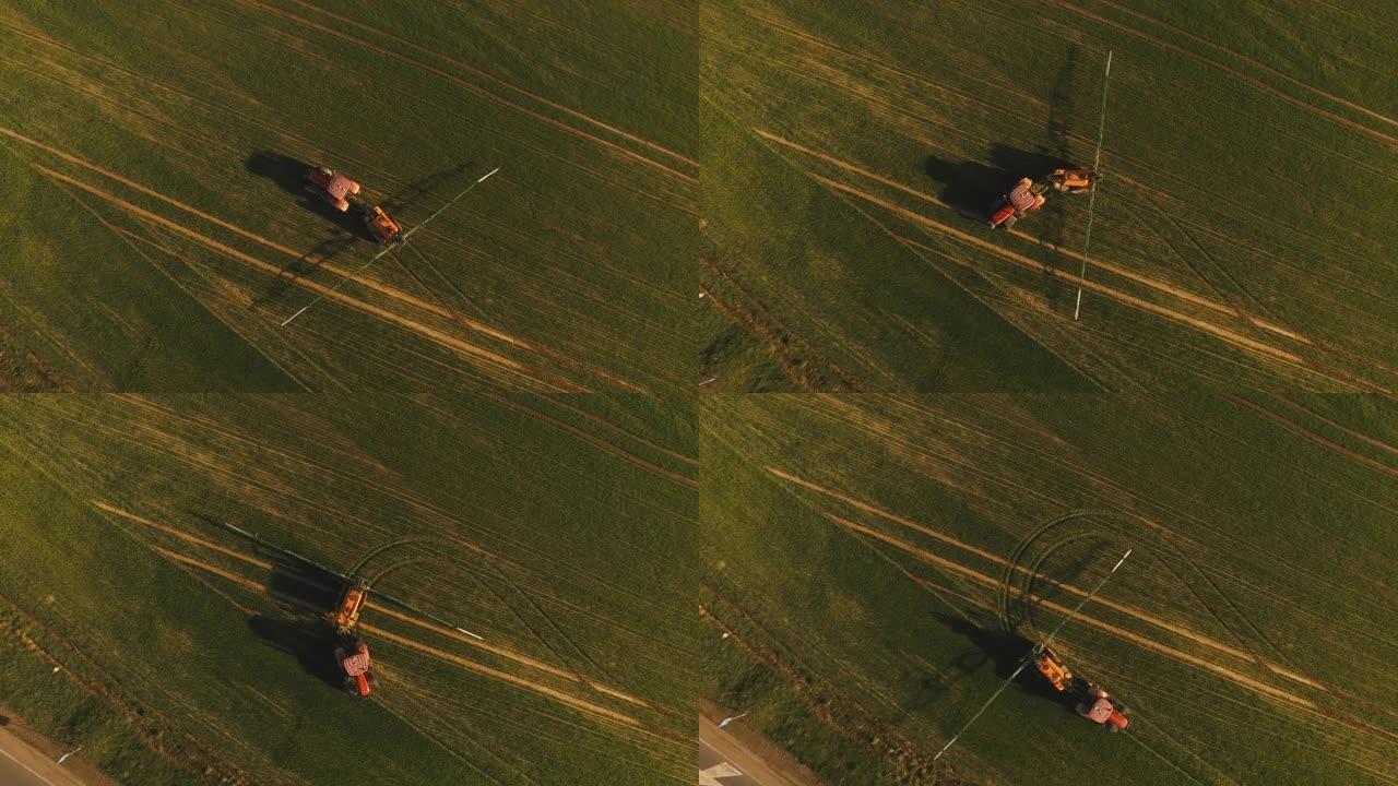 日落时用喷雾器，除草剂和农药在田间喷洒的农用拖拉机的鸟瞰图。农用机械向绿地喷洒杀虫剂，农业自然季节春