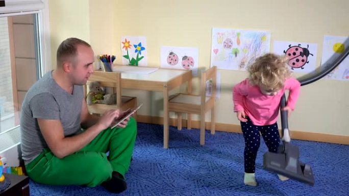 父亲男子使用平板电脑和小女儿女孩徘徊在地板上