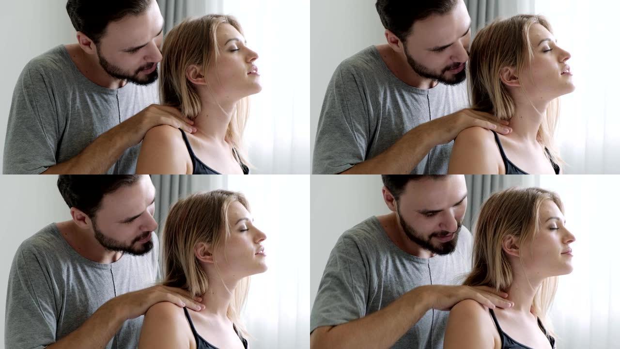 男人在床上给女人做肩部按摩的侧面照片。高加索男人和女人。胡子、爱情和关系概念。