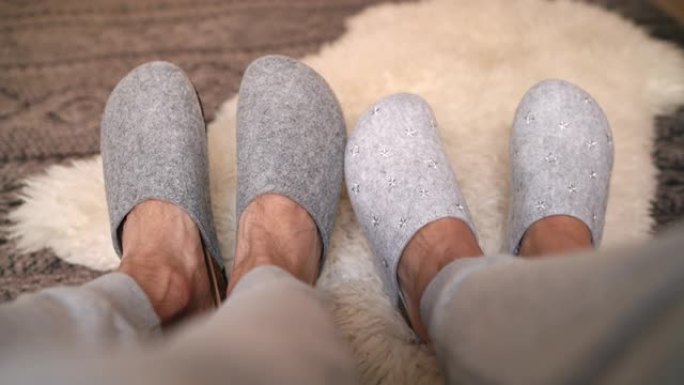 这两双新的灰色家居拖鞋，男女坐在床上，脚在舒适的卧室里有趣地移动。家庭甜蜜家庭概念4K UHD电视画