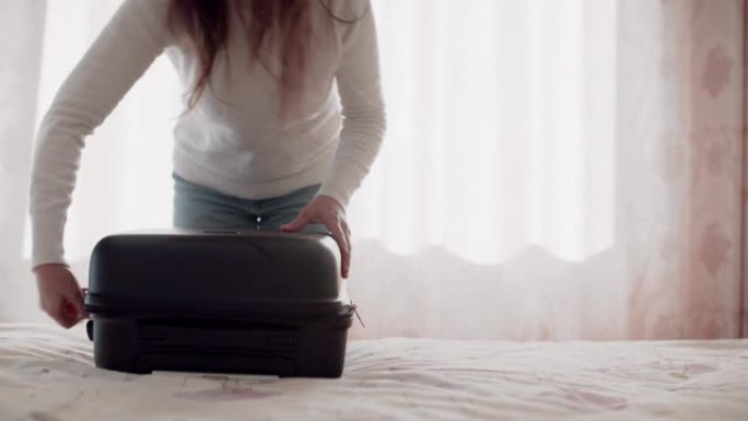 年轻女子单人旅行者从最后一次旅行中打开行李箱。带着黑色手提箱去度假。出差。