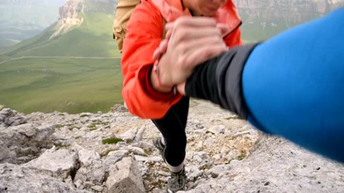 在多岩石的高原和地平线的背景下，快乐的登山者到达山顶，拥有令人惊叹的景色。互助团队的概念。实时摄像机