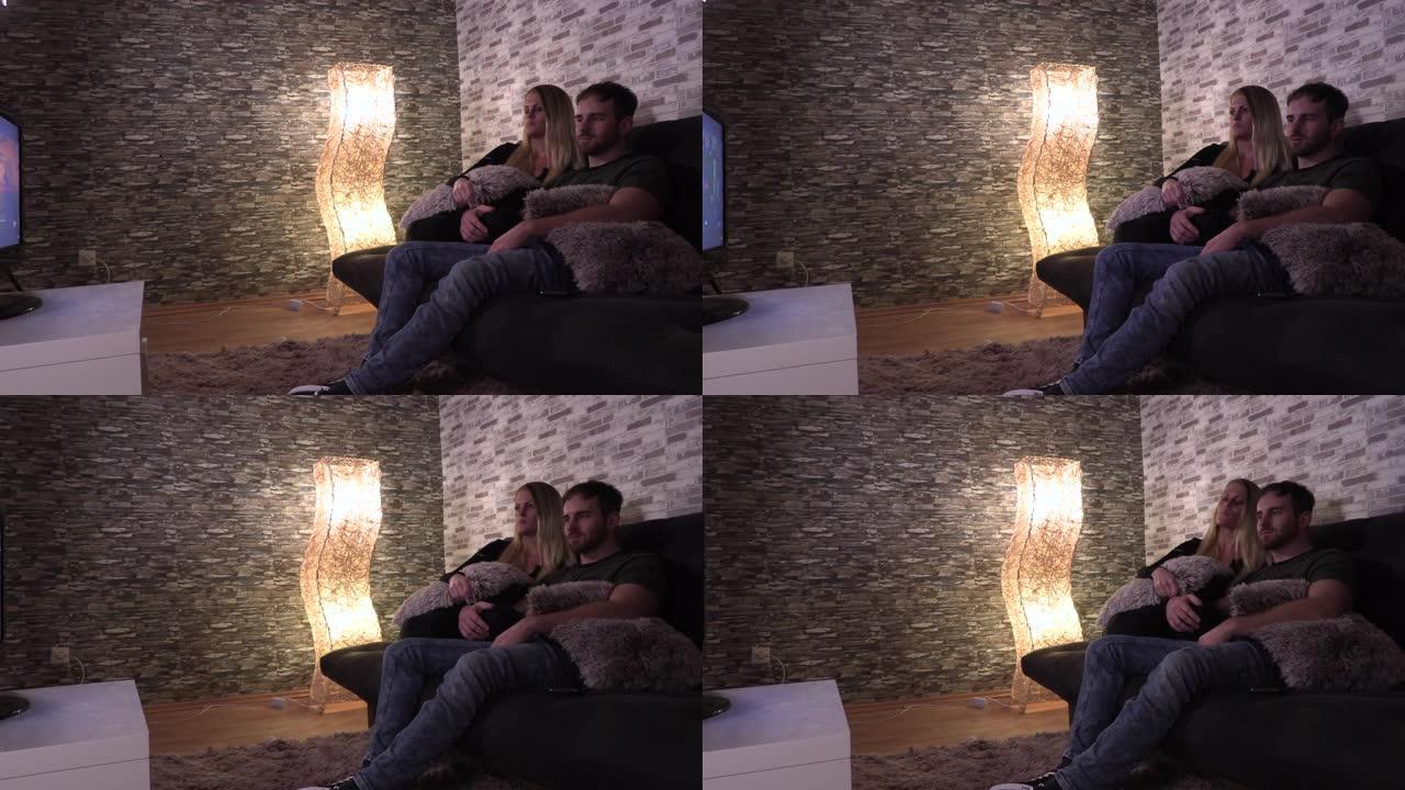 情侣在大厅的沙发上拥抱着看电视
