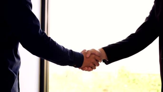 两名商人企业家或工作面试进展顺利，并以自信的慢动作握手。