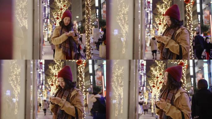 亚洲女孩戴上羊毛帽子和围巾。她在城市的圣诞市场购物。