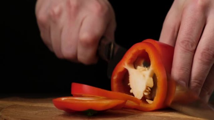 刀在木板上切厨房里的红辣椒。特写。